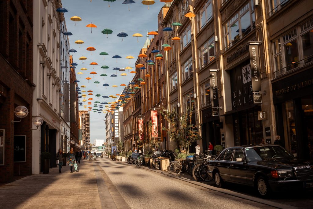 Bunte Regenschirme über den Großen Bleichen im Passagenviertel, Blick in die Straße mit Backsteinfassaden